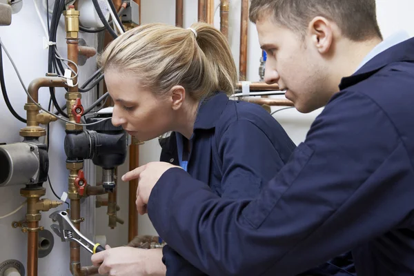 Vrouwelijke stagiair loodgieter werken aan centrale verwarming boiler — Stockfoto