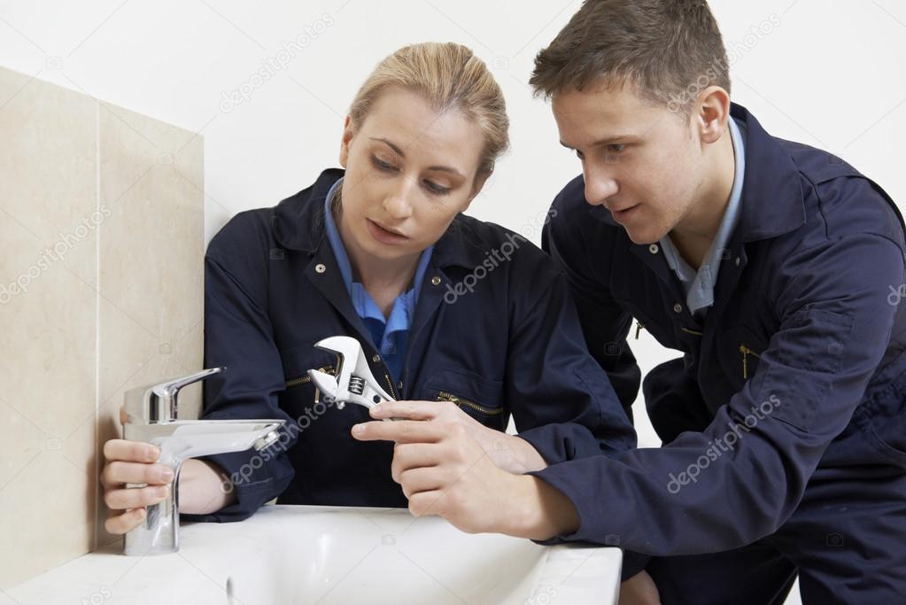 Female Trainee Plumber Working On Tap In Bathroom