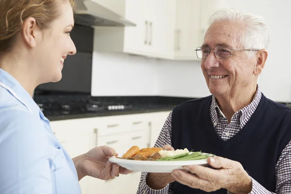 Cuidador servindo almoço para o homem sênior — Fotografia de Stock