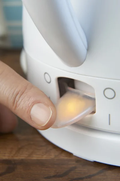 Gros plan de la femme allumant le commutateur d'alimentation de la bouilloire — Photo