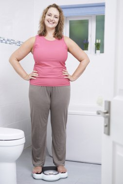 Mutlu kadın kendini ölçeklerde banyoda Tartım