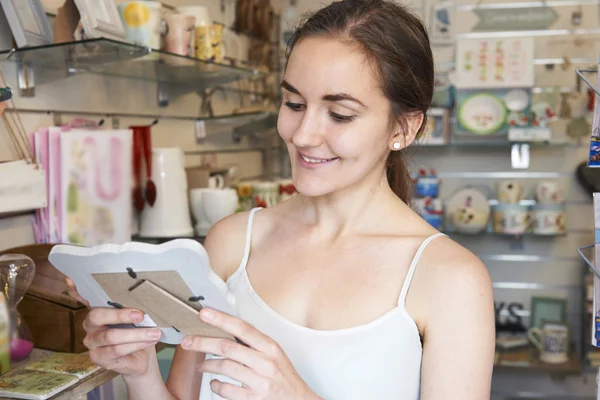 Kadın shopper fotoğraf çerçevesi hediye dükkanında bakıyor — Stok fotoğraf