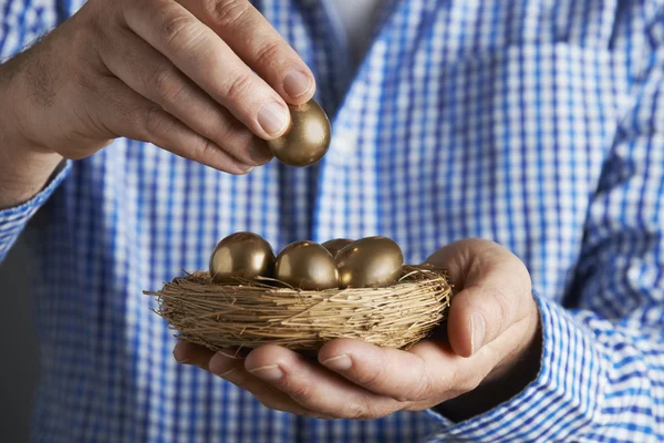 Человек, держащий гнездо, полное золотых яиц — стоковое фото