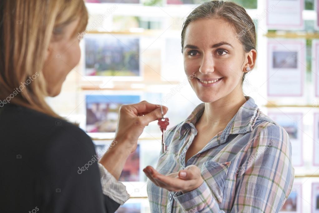Woman Collecting Keys To Property From Estate Agent