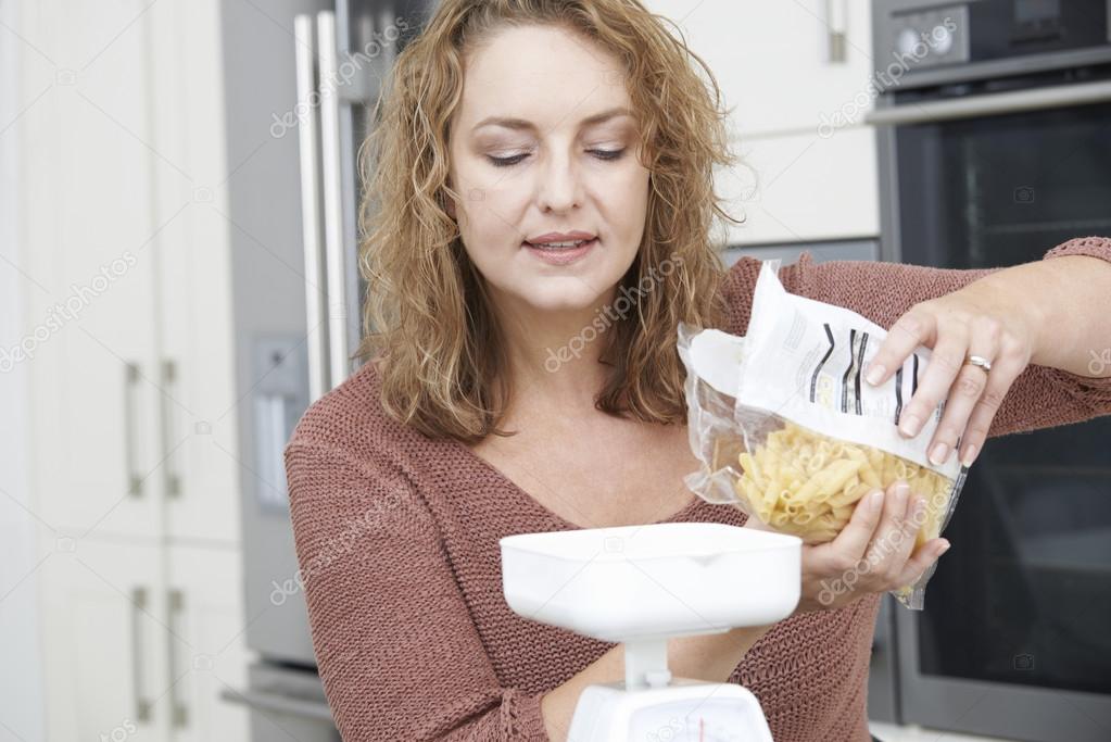 Plus Size Woman On Diet Weighing Out Pasta For Meal