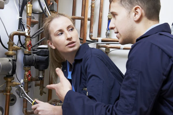 Vrouwelijke stagiair loodgieter werken aan centrale verwarming boiler — Stockfoto