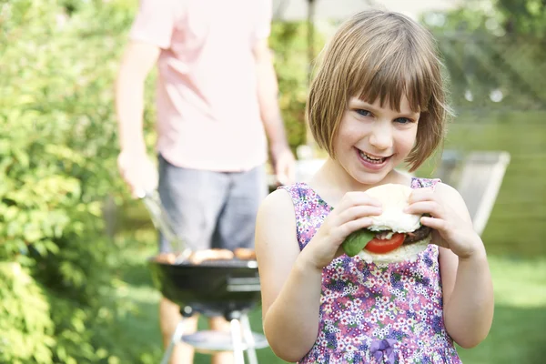 Jong meisje Beefburger eten bij familie barbecue — Stockfoto