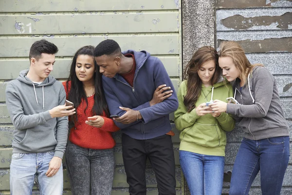 Grupo de adolescentes que comparten mensajes de texto en teléfonos móviles — Foto de Stock