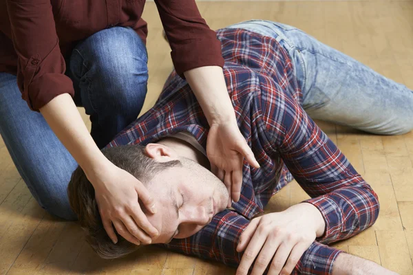 Woman Placing Man In Recovery Position After Accident — Stock Photo, Image