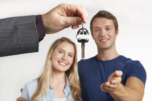 Dealer Handing Over Keys For New Car To Young Couple — Stock Photo, Image