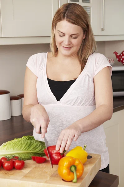 Mujer embarazada picando verduras frescas — Foto de Stock