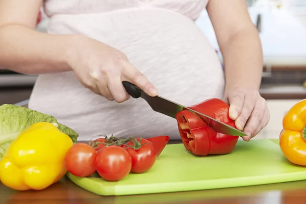 Mujer embarazada picando verduras frescas — Foto de Stock