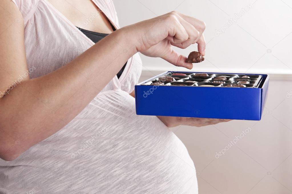 Detail Of Pregnant Woman Eating Box Of Chocolates