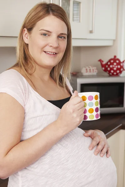 Gravid kvinna avkopplande med varm dryck — Stockfoto