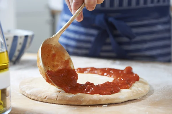 Close Up Of Adding Tomato Sauce to Pizza Base — стоковое фото