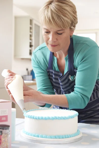 Žena doma námrazy narozeninový dort v kuchyni — Stock fotografie