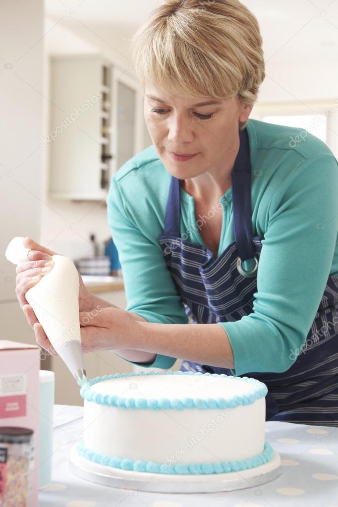 Woman Icing Birthday Cake In Kitchen At Home