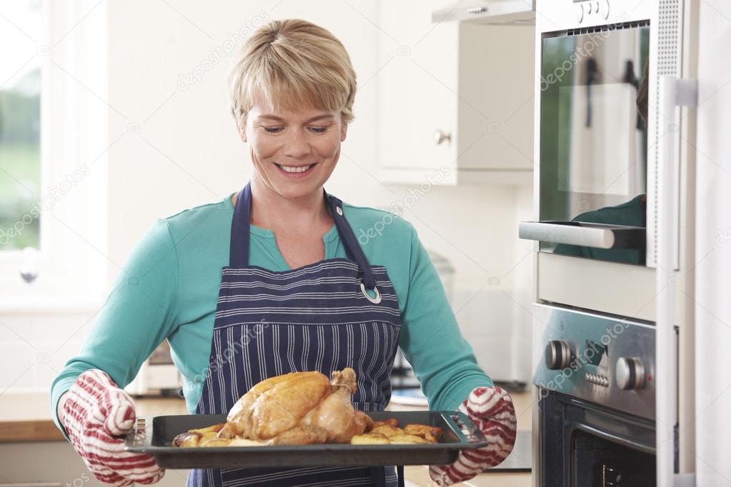 Woman In Kitchen Holding Tray With Roast Chicken