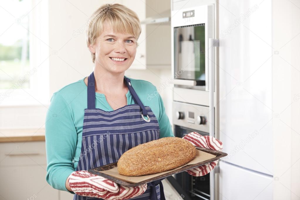 Woman Taking Home Baked Loaf Out Of Oven