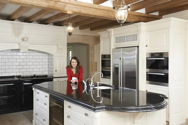 Mujer madura de pie en la nueva cocina amueblada de lujo — Foto de Stock