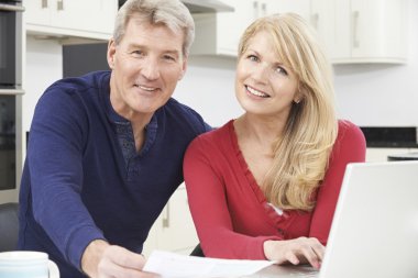 Smiling Mature Couple Reviewing Domestic Finances clipart