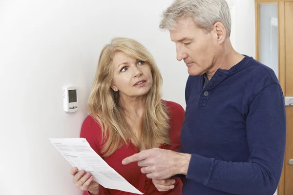 Besorgtes älteres Ehepaar mit Rechnung dreht Zentralheizung ab — Stockfoto