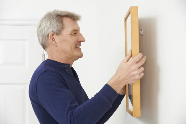 Mature Man Hanging Picture On Wall — Stock Photo, Image