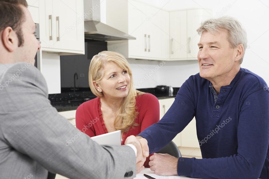 Mature Couple Shaking Hands With Financial Advisor At Home
