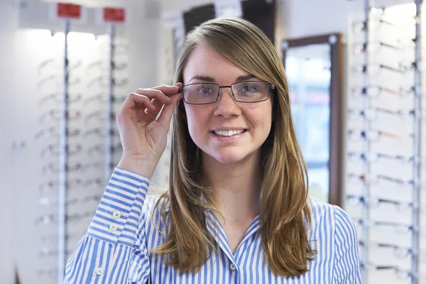 Kvinnan försöker på nya glasögon i optiker — Stockfoto