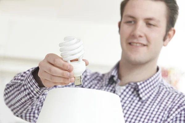 Man sätta låg energi glödlampa i lampa hemma — Stockfoto