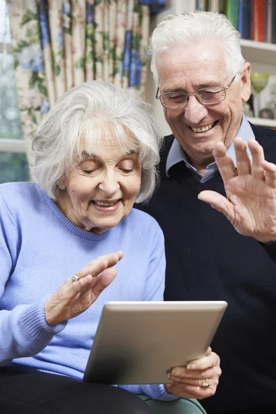 Старшая пара с помощью цифрового планшета для видеозвонка с семьей — стоковое фото