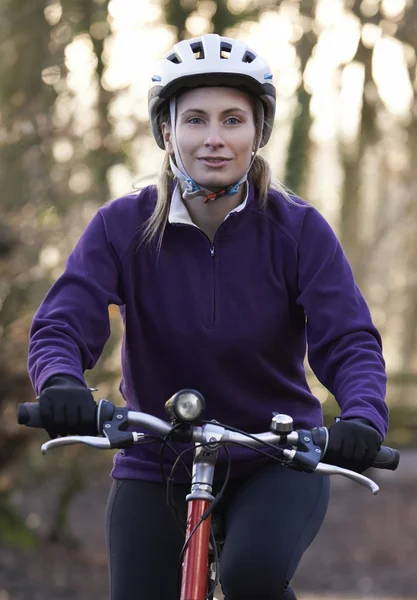 Mujer montando en bicicleta de montaña a través de bosques — Foto de Stock