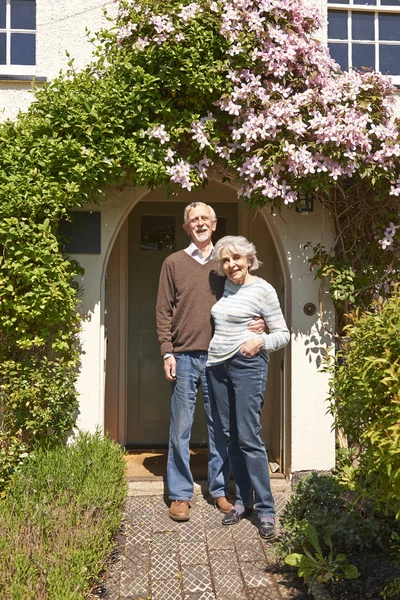 Συνταξιούχο ζευγάρι στέκεται έξω από όμορφο εξοχικό σπίτι — Φωτογραφία Αρχείου