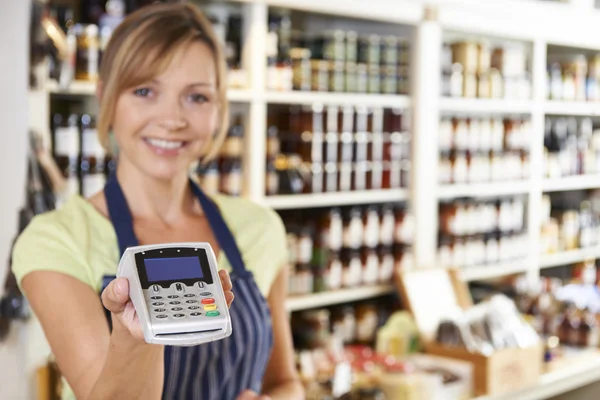 Asistente de ventas en la tienda de alimentos entrega de la máquina de tarjeta de crédito a Cus — Foto de Stock