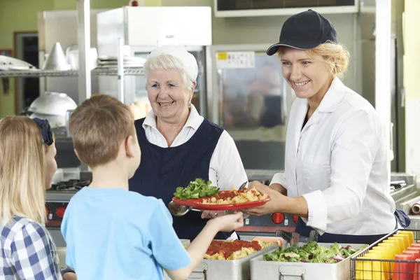 Leerlingen In School cafetaria wezen Lunch geserveerd door diner dames — Stockfoto