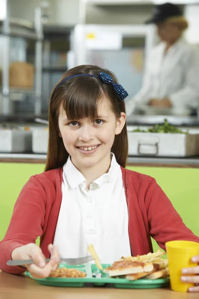 Schülerin sitzt in Schulmensa am Tisch und isst Ungesundes — Stockfoto