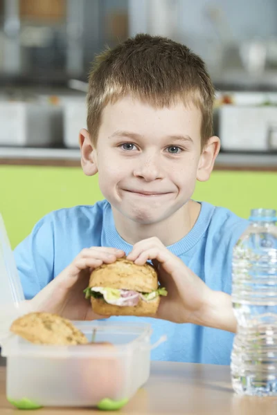 Alumno masculino sentado en la mesa en la cafetería escolar comiendo sano P — Foto de Stock