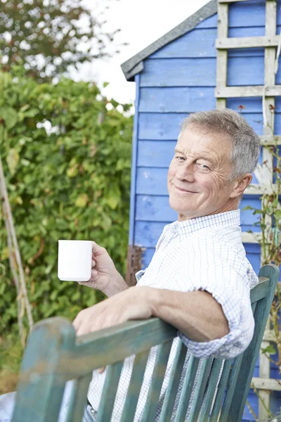 Starší muž relaxační v zahradě s šálkem kávy — Stock fotografie