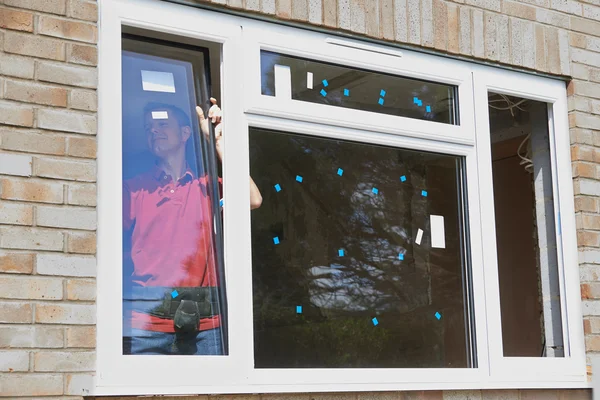 Bouwvakker installeren van nieuwe ramen in huis — Stockfoto