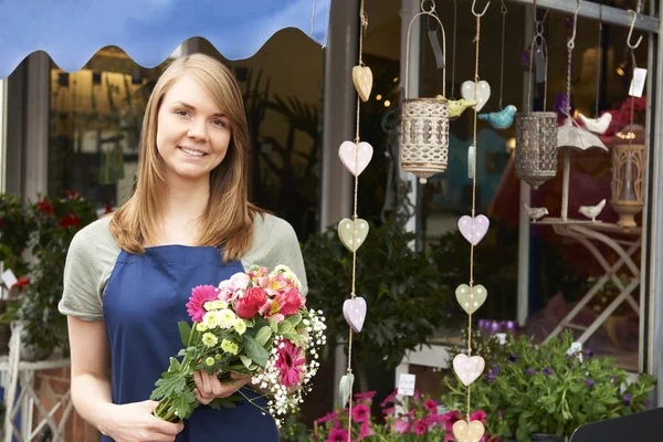 Fleuriste debout à l'extérieur de la boutique avec beaucoup de fleurs — Photo