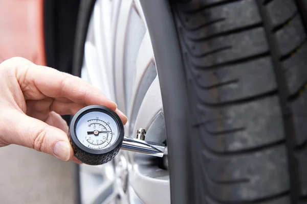 Primer plano del hombre que comprueba la presión del neumático del coche con el indicador — Foto de Stock