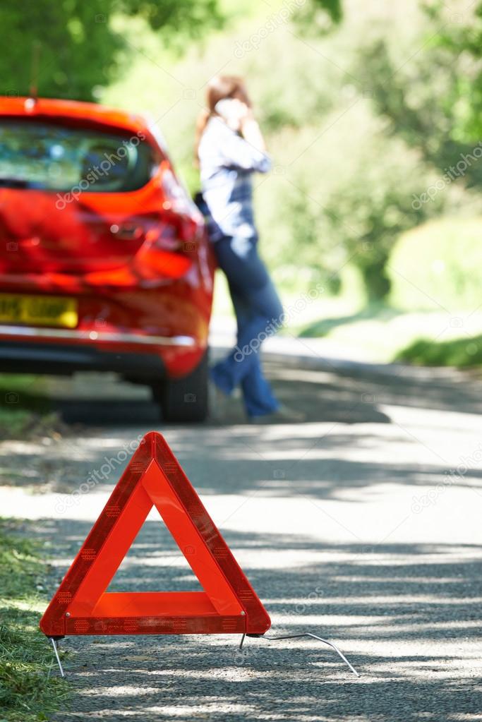 Female Driver Broken Down On Country Road With Warning Sign In F