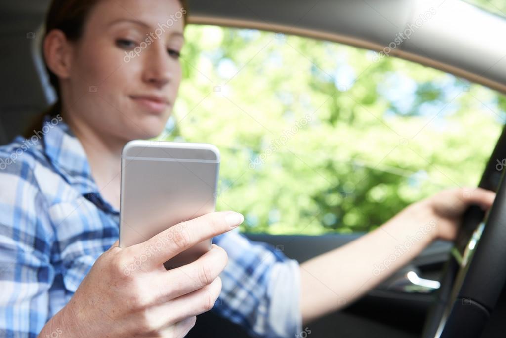 Woman In Car Texting On Mobile Phone Whilst Driving