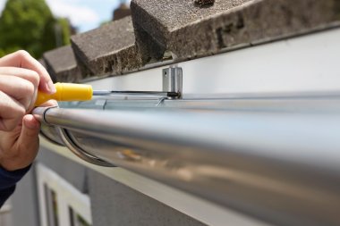Close Up Of Man Replacing Guttering On Exterior Of House clipart