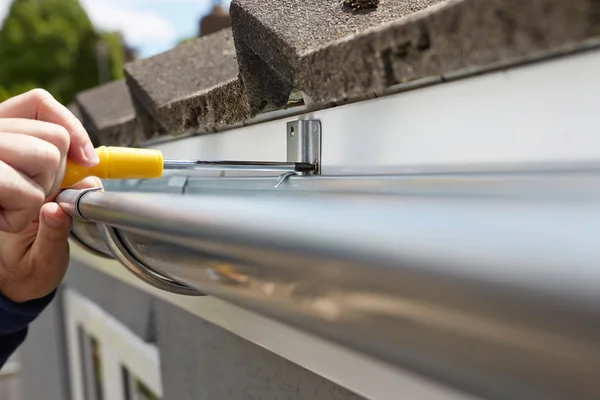 Close Up Of Man Replacing Guttering On Exterior Of House Stock Picture