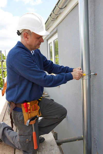 Handwerker ersetzt Dachrinnen an Hausfassade — Stockfoto