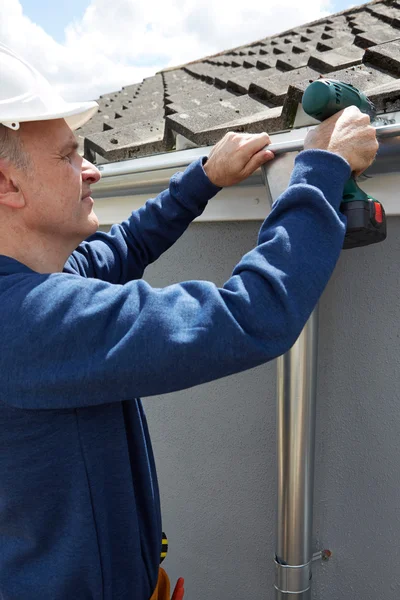 Handwerker ersetzt Dachrinnen an Hausfassade — Stockfoto