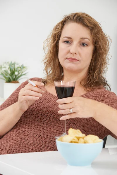 Женщина курит сигарету, пока пьет вино и ест закуски — стоковое фото