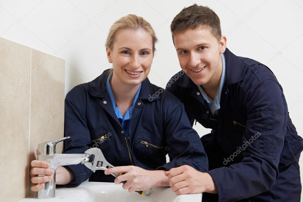 Female Trainee Plumber Working On Tap In Bathroom