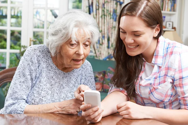 Teenager-Enkelin zeigt Großmutter, wie man Handy benutzt — Stockfoto